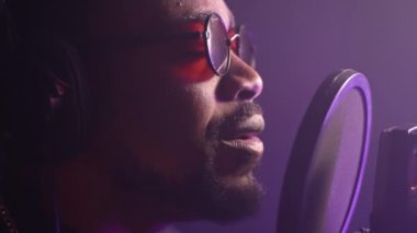 Duygusal siyahi şarkıcı müzik stüdyosunda yeni bir şarkı kaydediyor. Yakışıklı yüzün yakın plan portresi. Yetenekli Afrikalı Amerikalı şarkıcı yeni bir soul ya da pop şarkısı söylüyor.