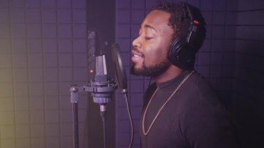 Ses prodüksiyonu için profesyonel ekipman, izolasyon kabininde şarkı söyleyen siyah şarkıcı, yakışıklı Afrikalı adam güzel romantik kompozisyon yapıyor, radyoda ses yeteneği gösterisi