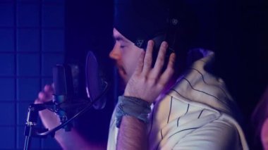 Profesyonel erkek ve kadın şarkıcıların ses geçirmez ses stüdyosunda lirik bir düet şarkısı kaydettiği yavaş çekim. Müzik üretimi