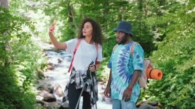 Sosyal medya için vahşi ormanda yürüyüş yaparken selfie çeken bir çift genç adam ve kadın. Seyahatten fotoğraf ve video çekiyorum. Aile, yolculuk, yürüyüş, seyahat, turizm. Dağda yaz tatili.