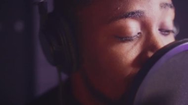 Müzik stüdyosunda romantik bir şarkı söyleyen siyahi bir şarkıcının yakın çekim yavaş çekimi. Yeni bir albüm kaydediliyor
