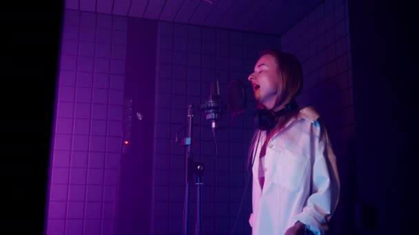 女人在专业的录音室里唱抒情歌曲 站在麦克风旁的隔离室里 有才华的流行歌曲 现代音频制作 录音和叮当的女歌手 — 图库视频影像
