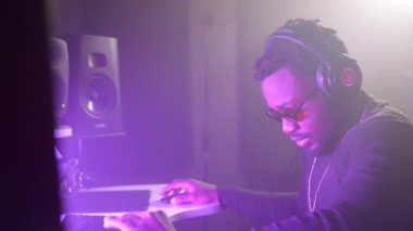 Modern ses kayıt stüdyosunda çalışan profesyonel siyah ses mühendisi, mühendislik odasında oturuyor, çoklu monitör kurulumu, rap ve hip-hop müzik tarzıyla dijital ses çalışma istasyonunda çalışıyor.