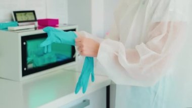 Doktor diş hekimliğindeki sterilizasyon makinesinden aletleri almak için eldiven takıyor, elleri yakın plan. Sterilizasyon için ultraviyole otoklav sterilizatörü, sterilizasyon için ultraviyole termostat diş ve cerrahi aletler.