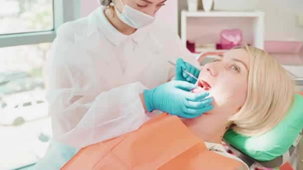 現代の歯科医院 椅子の女性患者 歯を検査する女性医師 爪と歯の腐敗を探しているセラピスト 歯の痛みを治癒し 病気を予防する — ストック動画