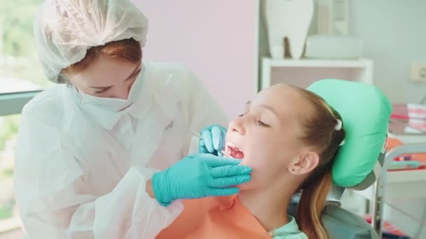 十代の少女の歯と歯茎を調べる女性の物理学者 歯の病気や歯科の予防 子供のための医療と医療保険 現代的な設備を備えた現代の診療所 — ストック動画