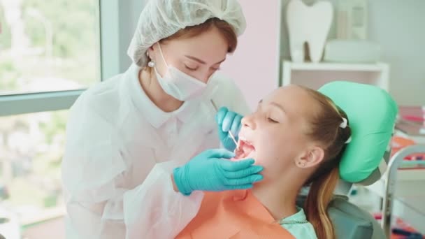 歯科の歯科鏡を使用して歯科の10代の子供の少女の歯を検査する歯科医の女性 医師の症候群学者は 症候群診療所のティーンエイジャーを 診察する予定です 歯医者を訪問する — ストック動画