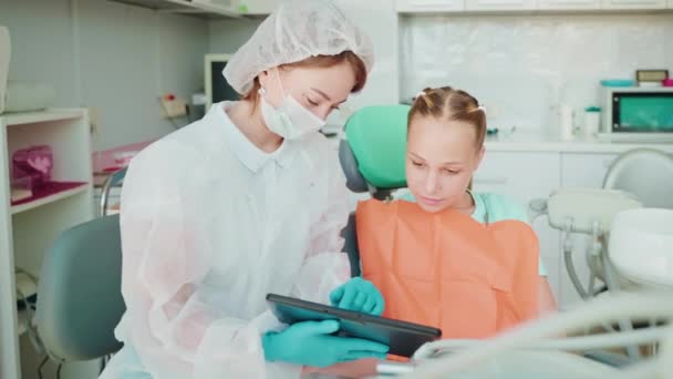 Tandläkare Visar Utbildningsvideo Surfplatta Till Tonåring Flicka Patient Inom Tandvården — Stockvideo