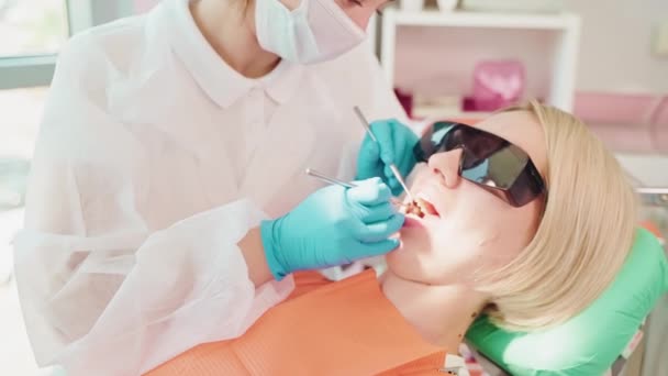 現代の歯科医院 女性の歯を検査する女性の症候学者 毎年検査および余分な治癒の歯の痛み ヘルスケアおよび医療保険のカレッジ — ストック動画