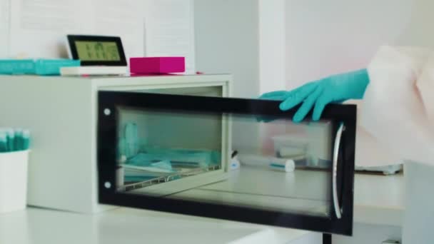 現代の病理学の診療所 医者は任命の患者のための道具を準備し 紫外線殺菌箱から滅菌用具を取りましたり 滅菌手袋の手の手を見ます — ストック動画