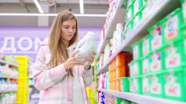 Zorgvuldige Blonde Meisje Kiezen Vloeibare Wasmiddel Fles Detailhandel Supermarkt Jonge — Stockvideo