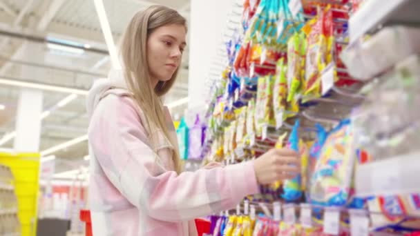 超市里的女性顾客 肖像画 选择小吃的女人 观看不同包装的人 在杂货店里购买不健康有害食品和糖果的人 — 图库视频影像