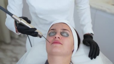 Kadın güzellik salonu seansı yapıyor. Kozmetik uzmanı, yüz terapisi için YAG lazeri sağlıyor. Yaşlanma karşıtı tedavi