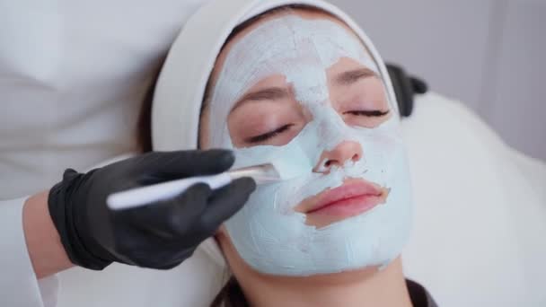 一个女人用黏土面罩接受面部治疗的特写镜头 化妆品和温泉 — 图库视频影像