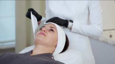 Kozmetik kliniğinde yüz ve cilt için prosedür, kadın kanepede uzanıyor, tedaviyi, cilt bakımını ve anti-yaş güzellik terapisini yenilemeye hazırlanıyor