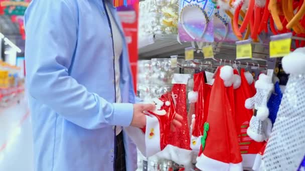 Hombre Eligiendo Santa Sombrero Supermercado Tipo Que Compra Decoraciones Navideñas — Vídeos de Stock
