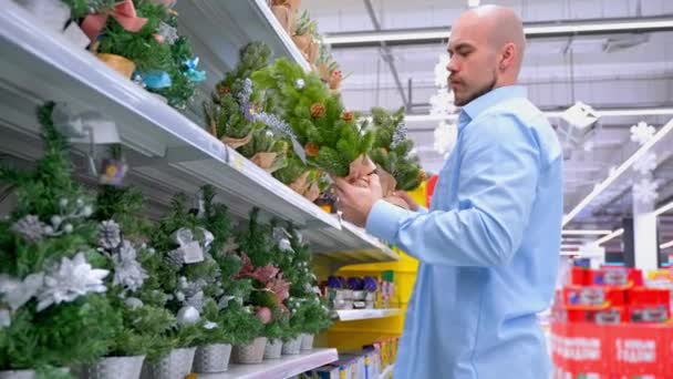 Guy Wybrać Małe Choinki Supermarkecie Człowiek Bierze Różne Drzewa Gabloty — Wideo stockowe
