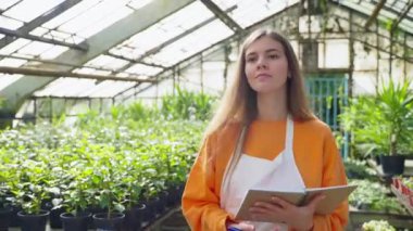 Modern serada kadın bahçıvan, bitkiler, modern tarım sektörü ve eko teknolojili tarım organik bitkileri arasında yürüyen profesyonel tarım uzmanının portresi
