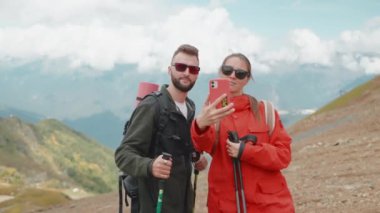 Gülümseyen turistler dağ yamacında telefonla selfie çeken kadın yürüyüşçüler. Gezginler tatilde ailelerini tepelerde bir araya getirirler. İnsanlar kendilerini akıllı telefondan fotoğraflıyorlar..
