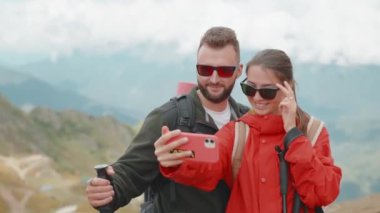 Gülümseyen dağcılar, turistler dağ vadisinde selfie çeken kadın yürüyüşçüler. Tatilde birlikte dağlarda gezen bir aile. Akıllı telefondan fotoğraf çeken genç bir çift..