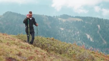 Dağlarda yürüyüş yapan gezgin adam ellerinde çubuklarla vadide geziyor. Tepelerde turist yürüyüşü. Gezgin doğada yeni vahşi yerleri keşfediyor. Dağ zirveleri olan muhteşem bir manzara..