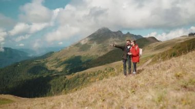 Yürüyüş yapan turistler, dağ yamacında yürüyüş yapan bir adamla bir kadın güzergahı tartışıyorlar. Gezginler, dağlarda birlikte yürüyen aileleri keşfediyorlar. Vahşi doğada yolculuk..