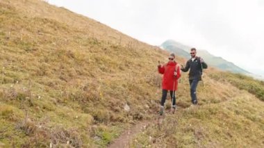 Yürüyüşçüler kadın ve erkek ellerinde sopalarla dağda dar bir yolda yürüyorlar. Gezginler seyahate çıkar, vahşi doğada birlikte macera yaşarlar. Dağcılar tepeye tırmanıyor, zirveye tırmanıyor. Yürüyüş konsepti.
