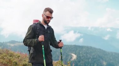 Kendine güvenen sırt çantalı biri dağ yamacında yürüyor, kuzey yürüyüşü için çubuklar kullanıyor, dağlık arazide eko-turizm yapıyor, hafta sonu veya tatilde aktif ve sportif dinleniyor, dağın tepesinden nefes kesici manzaralar.
