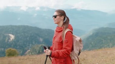 Dağlarda yürüyüş yapan kadın turist portresi. Yamaçta ellerinde çubuklarla yürüyorlar. Kaşif kız tepelerde geziniyor. Gezginlerin doğada maceraları vardır. Seyahat tutkusu turizm tatili.
