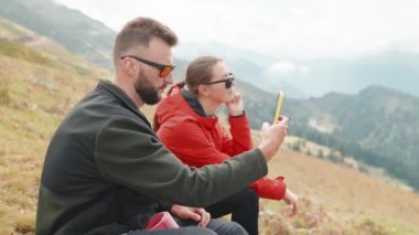 Çift dağ yamacında oturur ve insan telefonda doğanın inanılmaz videosunu kaydeder. Turistler tatilde zirveye tırmanmak için birlikte mola veriyorlar. Yürüyüşçü kız seyahatte konuşuyor..