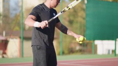 Teniste düşük voleybol antrenmanı yapan bir adam. Sporcu topa vuruyor, profesyonel spor antrenmanında sahada düşük servis yapıyor. Egzersiz, tenis antrenmanı. Hobi, spor konsepti.