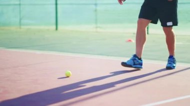 Adam saha yüzeyinde topa vuruyor. Tenis oyuncusu dışarıda antrenman yapıyor. Profesyonel spor egzersizleri, fiziksel egzersizler, açık havada tenis atışları pratiği. Profesyonel spor oyunu oynuyorum..