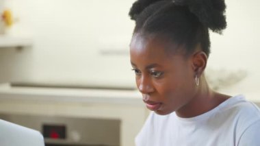 Dizüstü bilgisayarda çalışan serbest çalışan bir kadın. Ciddi Afro-Amerikan kız portresi kıvırcık at kuyruklu bilgisayar ekranındaki yazı tipine bakıyor. Serbest, dijital göçebe, uzaktan çalışma konsepti.