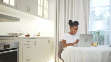 Siyah kadın serbest çalışan, evde çalışan, dizüstü bilgisayarla daire mutfağında çalışan genç Afrikalı kadın portresi, dijital göçebe ve internet işi, tasarımcı veya pazarlama uzmanı.