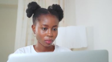 Portre, merkezi ofiste dizüstü bilgisayarda çalışan Afrikalı Amerikalı serbest bir kıza odaklanmış. Kıvırcık at kuyruklu ciddi bir kadın. Serbest iş, dijital göçebeler yaşam tarzı kavramı. Bilgisayarda yazı okunuyor.