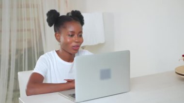 Kadın laptopta video kullanıyor, video konferansında sohbet eden Afro-Amerikan kadın portresi, gülümseyen ve sallanan kamera, blog yazarı ya da serbest çalışan.
