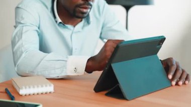Tabletle çalışan işadamı, ellerin kapalı olması, sensör ekranında anlaşmalar imzalaması, modern cihazları olan Afrikalı Amerikalı bir adam.