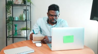 Afro-Amerikan özenli bir adam not defterine not alıyor. Ana ofisteki dizüstü bilgisayara bakıyor. Sakallı dijital göçebe serbest çalışıyor. Blogger programcı pazarlamacı analist tasarımcı.