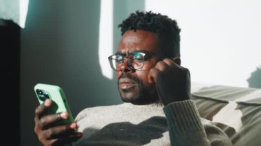 Gerçekten gergin bir adam telefon ekranına bakıyor kulaklığı kulaklığa takıp müzik dinliyor ya da video izliyor. Portre, elinde akıllı telefonuyla gözlüklü Afro-Amerikan bir adama çatıyor..