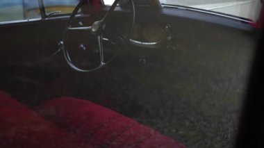 Salon direksiyonu retro vagonda. Kırmızı kadife, eski model Plymouth otomobilinde siyah deri direksiyonda durur. Yüzyılın ortası arabası. Araba koleksiyonu sergisi otomobil üretim geçmişini kaydetti.