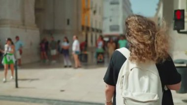Sırt çantalı kadın turist Lizbon 'da, Ticaret Meydanı yakınlarında sokakta yürüyor. Yazın tarihi binalara hayran kalıyor. Seyahat turizmi gezi gezisi konsepti.