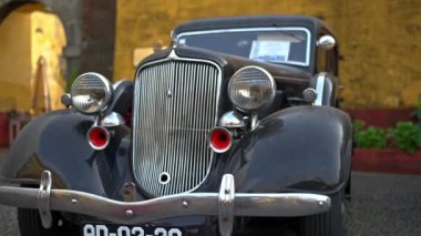 Eski şehrin caddesinde retro otomobil, siyah klasik arabanın ön görüntüsü, klasik tarz araç