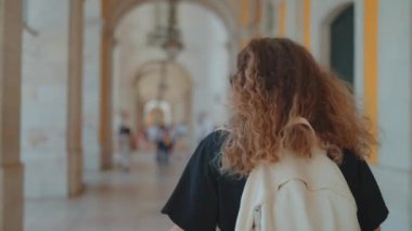 Dikiz manzaralı kıvırcık saçlı turist kadın Ticaret Meydanı 'nda yürüyordu. Tarihi eserlere hayran olunan bir binaydı. Avrupa 'da turizm gezisi Portekiz konsepti.