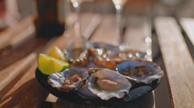 Lezzetli istiridye tabağı ve restoranın masasında limon, yakın görüş, romantik akşam yemeği ya da yazın kıyı şeridinde gastronomi gezisi, şarküterili yemekler ve lüks şampanyaların keyfini çıkarın.