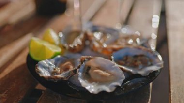 Güneşli bir günde açık hava lokantasında limonla servis edilen istiridyeler. Yenilebilir çiğ deniz ürünleri. Akşam yemeği, Akdeniz mutfağı sağlıklı gıda konsepti..