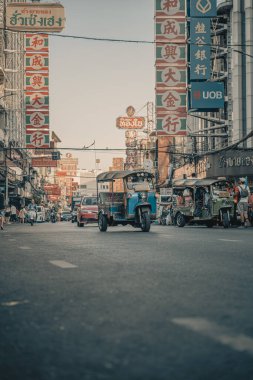 Bangkok Chinatown 'daki bir römorkun içinden detaylı bir görüntü, sürücüyü yakalamak, ayna yansımaları ve hareketli sokak aktiviteleri. Sahne Tayland kentinin canlı enerjisini yansıtıyor.