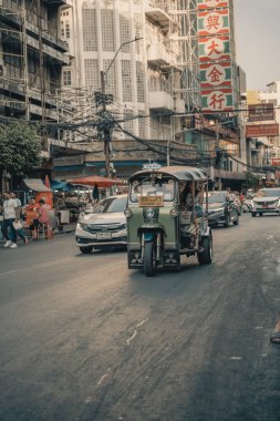 Bangkok Chinatown 'daki bir römorkun içinden detaylı bir görüntü, sürücüyü yakalamak, ayna yansımaları ve hareketli sokak aktiviteleri. Sahne Tayland kentinin canlı enerjisini yansıtıyor.