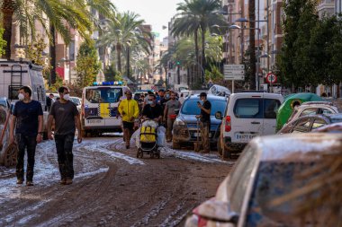 İspanya 'nın Valencia kentinde meydana gelen sel felaketinden sonra gönüllü ve vatandaşlar çamurla dolu bir caddede yol alıyorlar. Maske takarak ve temizlik malzemelerini taşıyarak, enkazı temizlemek ve bölgeyi eski haline getirmek için birlikte çalışıyorlar.. 