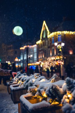 Karla kaplı büyülü bir Noel sahnesi. Bayram sokağının sıcacık ışığında usulca parlıyor..