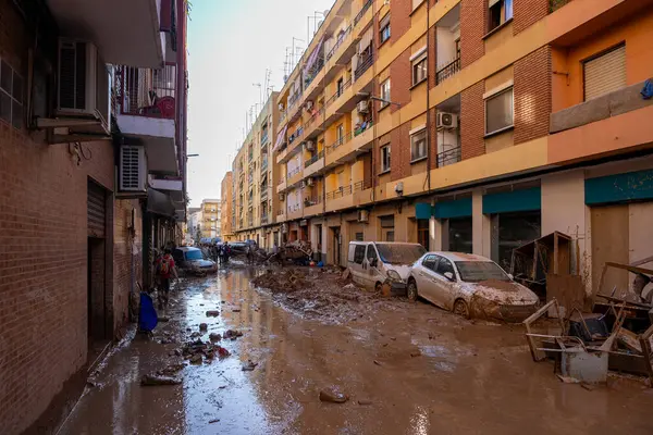 Fotoğraf Alfafar, Valencia, İspanya 'daki selin sonuçlarını gösteriyor. Gönüllüler, şiddetli sellerden sonra çamurlu bir caddeyi temizlemek için birlikte çalışıyorlar..